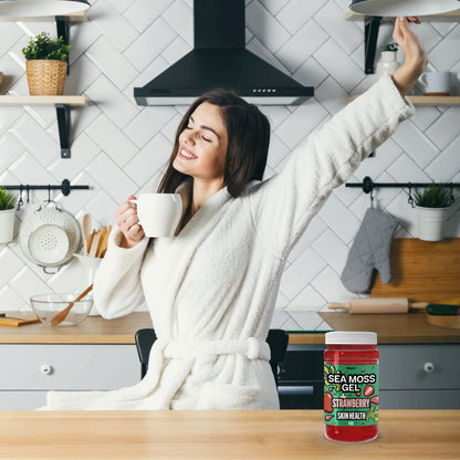 Woman enjoying a morning routine with coffee in the kitchen next to Biolore strawberry sea moss gel for daily wellness support.