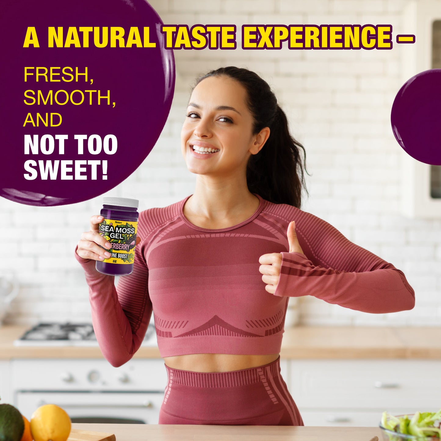 Woman in a kitchen holding elderberry sea moss gel and giving a thumbs up to highlight fresh smooth flavor that is not overly sweet.