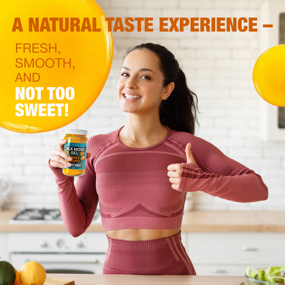 Woman holding mango pineapple sea moss gel in a kitchen, smiling and giving thumbs up to highlight fresh smooth taste that is not overly sweet.